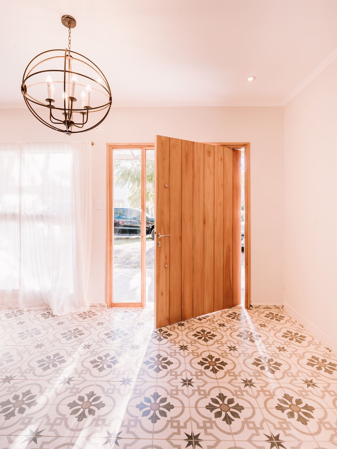 Hall de ingreso con piso calcáreo y puerta pivotante de madera
